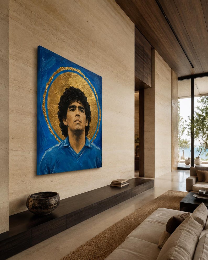 Puede incluir: Un cuadro rectangular sobre lienzo que muestra el retrato de un hombre de pelo rizado oscuro con una camisa azul de cuello. La figura se sit&uacute;a sobre un fondo azul vibrante con un gran halo circular dorado y texturizado alrededor de la cabeza.