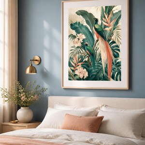 Puede incluir: Una l&aacute;mina de arte enmarcada que muestra dos aves quetzal posadas entre un exuberante follaje tropical, grandes hojas verdes de monstera y flores de color rosa p&aacute;lido. La obra est&aacute; en un marco de madera clara con un borde de paspart&uacute; blanco.