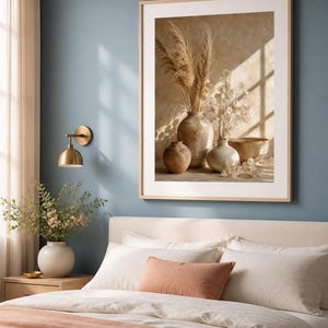 K&ouml;nnte beinhalten: Ein gerahmter Kunstdruck mit einem Stillleben aus drei Keramikvasen und einer Schale, gef&uuml;llt mit getrocknetem Pampasgras und Silberblatt-Stielen. Das Bild zeigt warme Beige- und Braunt&ouml;ne mit weichem Sonnenlicht und Fensterkreuzschatten.