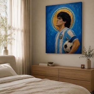 May include: A rectangular canvas painting depicting a man with dark curly hair wearing a light blue and white striped soccer jersey, holding a black and white soccer ball, set against a vibrant blue background with a circular gold halo.