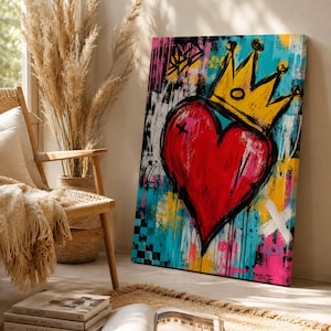 May include: A rectangular canvas painting featuring a large, vibrant red heart centered in the composition, topped with a bold yellow crown. The background is a chaotic mix of bright blue, pink, and yellow paint splatters with black brushstrokes.
