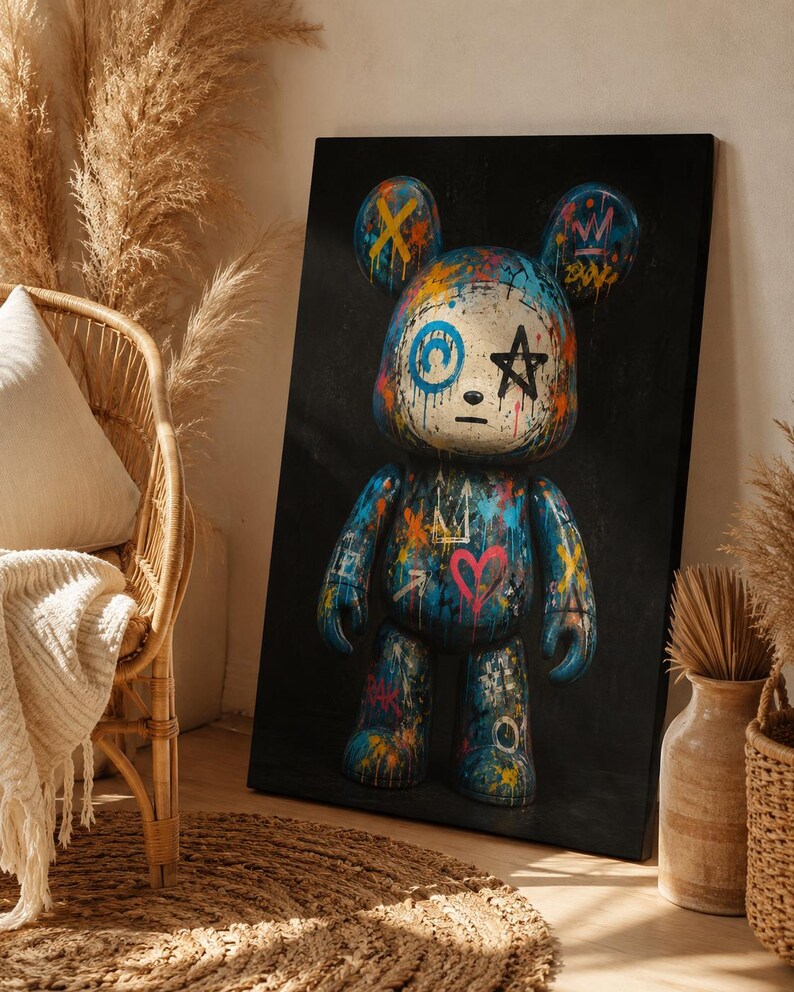 Op de afbeelding: Een rechthoekige canvasprint met een gestileerde berenfiguur tegen een effen zwarte achtergrond. De beer is versierd met levendige graffiti-achtige verfspatten, een roze hart, een zwarte ster en blauwe cirkelvormige markeringen.