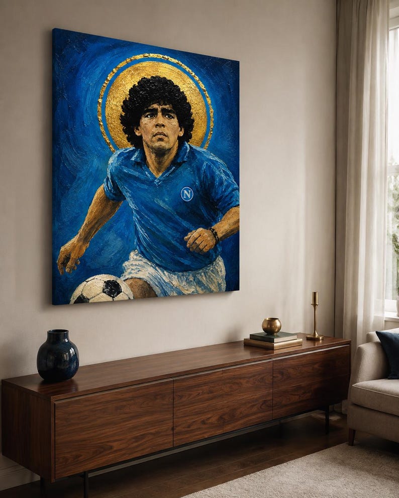 May include: A rectangular canvas painting depicting a soccer player with curly dark hair wearing a blue jersey with a white N logo and white shorts. The player is positioned in front of a large gold circular halo against a textured blue background.