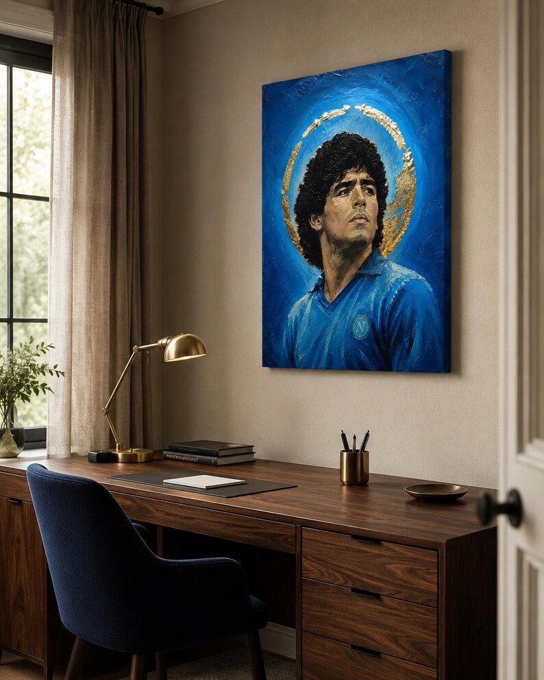 Puede incluir: Un cuadro rectangular sobre lienzo que muestra el retrato de un hombre de cabello oscuro y rizado con una camiseta azul de cuello. La figura se sit&uacute;a sobre un fondo azul intenso con un efecto de halo circular dorado y texturizado.
