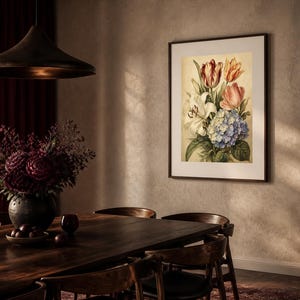 May include: A framed botanical wall art print featuring a bouquet of flowers including red and orange tulips, a white lily, and a cluster of blue hydrangea blossoms, displayed in a dark brown frame on a textured light beige wall.