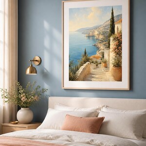Puede incluir: Una impresi&oacute;n de arte mural vertical enmarcada que representa un paisaje costero mediterr&aacute;neo con escaleras de piedra, macetas de terracota y cipreses con vistas a un mar azul bajo un cielo suave, en un marco de madera clara con paspart&uacute;.