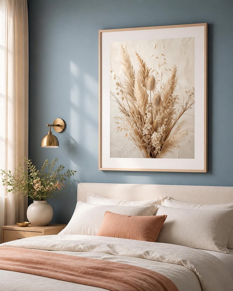 Pu&ograve; includere: Una grande stampa da parete rettangolare che raffigura una composizione di erba della pampa, cardi e fiori di campo essiccati nei toni del beige e del crema. L'opera &egrave; racchiusa in una cornice di legno chiaro su una parete blu tenue.