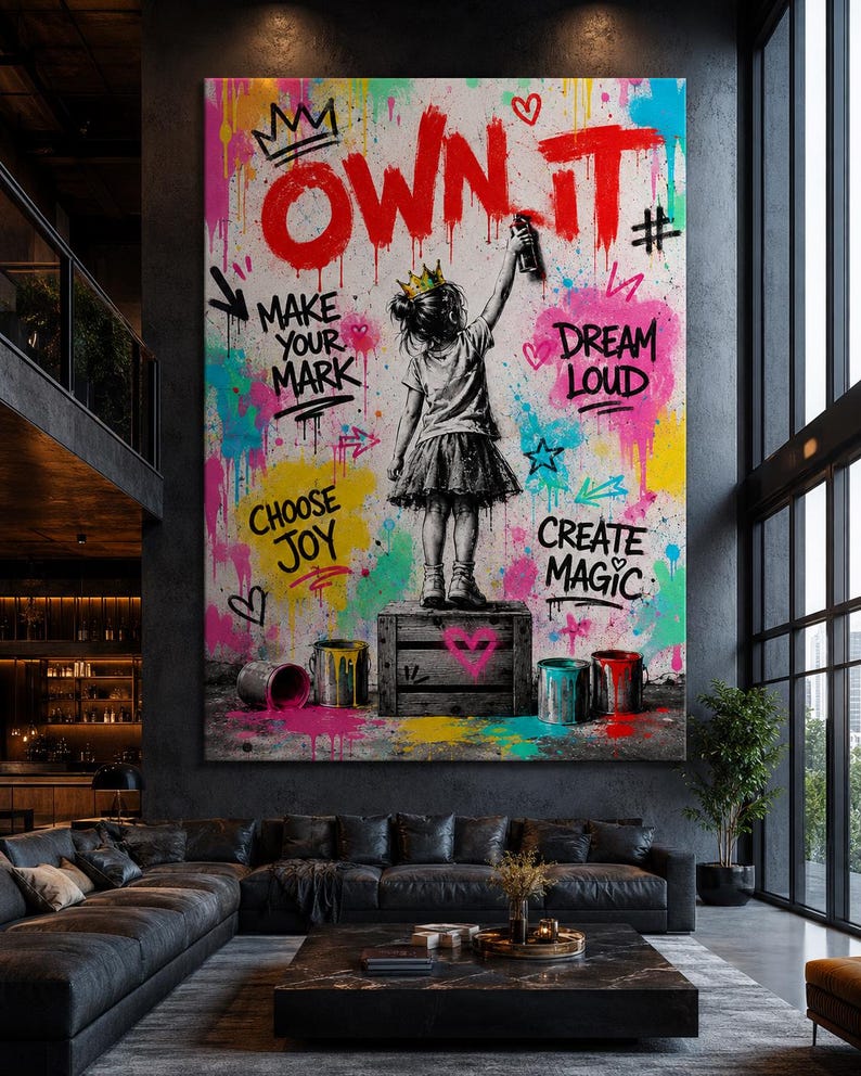 May include: A large rectangular wall art piece featuring a child wearing a crown, standing on a wooden crate and spray painting the text "OWN IT" in red. The background is a vibrant mix of colorful paint splatters, hearts, and stars with the phrases "MAKE YOUR MARK," "DREAM LOUD," "CHOOSE JOY," and "CREATE MAGIC."