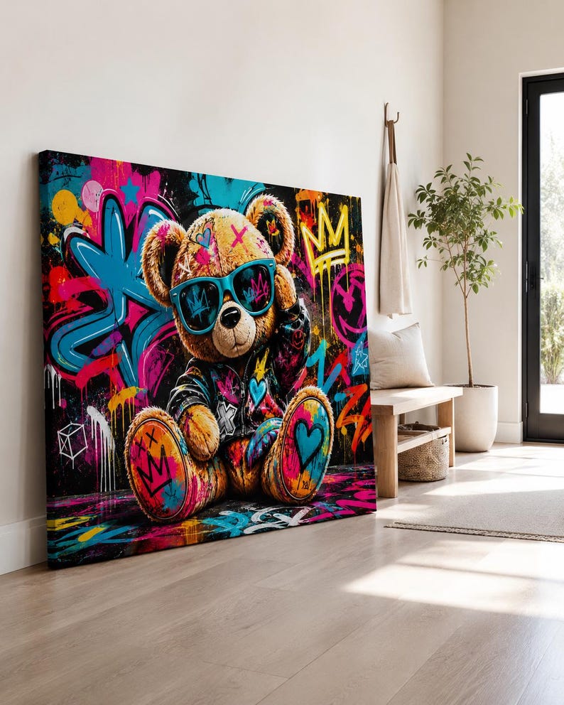 May include: A rectangular canvas print featuring a brown teddy bear wearing bright blue sunglasses and a dark jacket. The background is a vibrant graffiti-style mural with splashes of pink, blue, yellow, and black, including crown and heart motifs.
