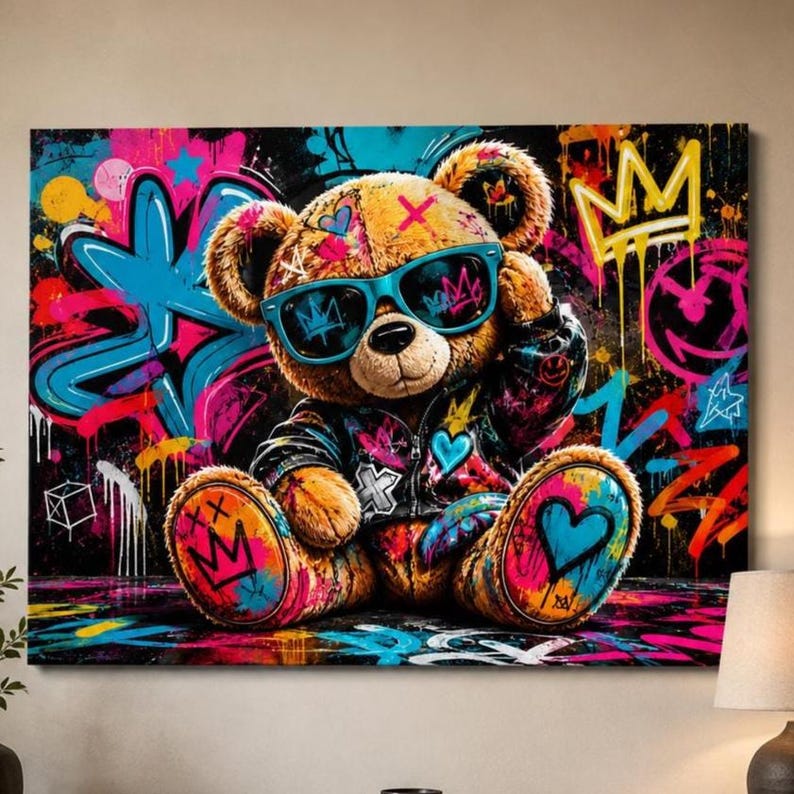 May include: A rectangular wall art print featuring a brown teddy bear wearing bright blue sunglasses and a dark jacket. The background is covered in vibrant graffiti-style street art with neon pink, blue, and yellow paint splatters and symbols.