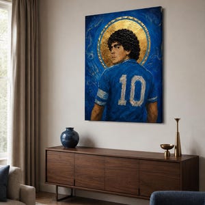 May include: A rectangular canvas painting featuring a portrait of a footballer with curly dark hair, wearing a blue jersey with the number 10 on the back. A large, circular gold leaf halo surrounds the head against a textured blue background.