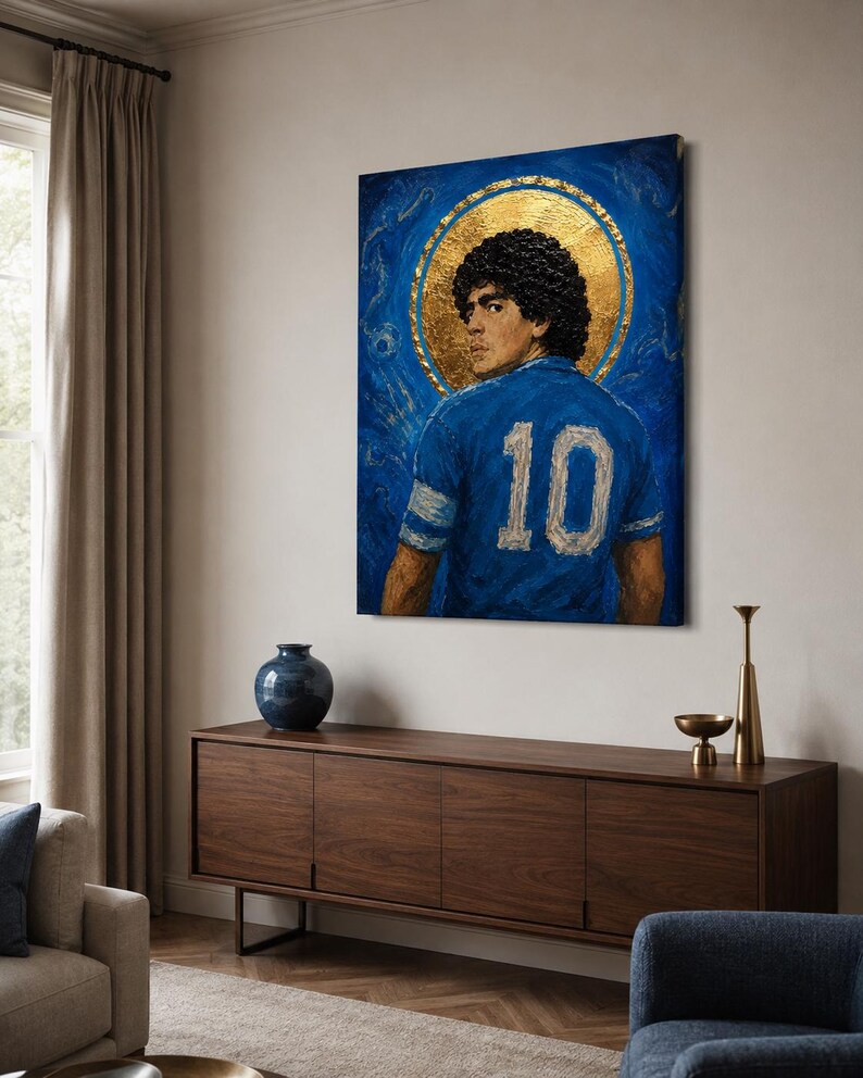 May include: A rectangular canvas painting featuring a portrait of a footballer with curly dark hair, wearing a blue jersey with the number 10 on the back. A large, circular gold leaf halo surrounds the head against a textured blue background.