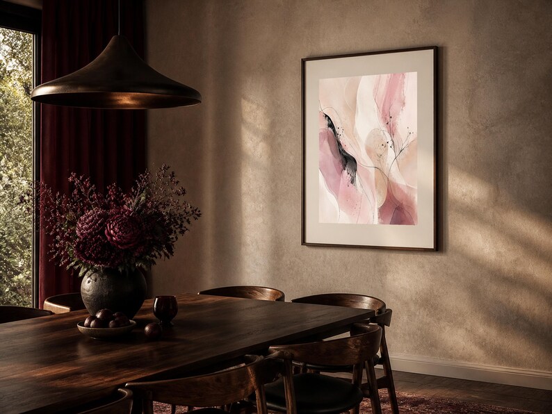 K&ouml;nnte beinhalten: Ein gerahmter abstrakter Wandkunstdruck mit flie&szlig;enden Formen in sanften Nuancen von Puderrosa, Creme und dunklem Mauve, akzentuiert durch feine, tintenartige schwarze Linien und kleine dunkle Sprenkel, pr&auml;sentiert in einem schmalen, dunklen Rahmen.