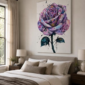 Puede incluir: Un gran cuadro rectangular de lienzo para pared que presenta una ilustraci&oacute;n central de una rosa morada cubierta con etiquetas, s&iacute;mbolos y salpicaduras de pintura al estilo grafiti. La rosa tiene tallo y hojas verde oscuro sobre fondo blanco.