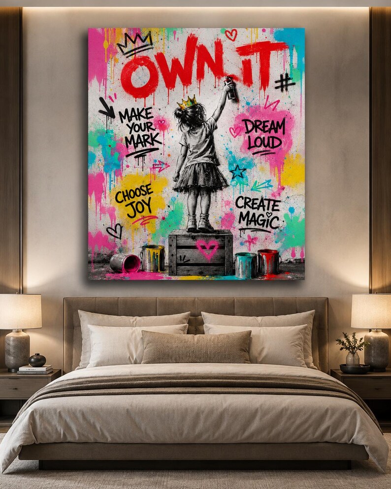 May include: A rectangular wall art print featuring a child wearing a crown standing on a wooden crate, spray painting the text OWN IT. The background is a vibrant graffiti-style splash of pink, yellow, and blue with the phrases MAKE YOUR MARK, DREAM LOUD, CHOOSE JOY, and CREATE MAGIC.