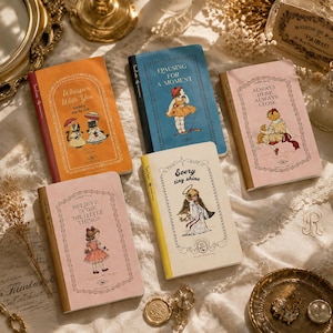 May include: Five rectangular notebooks with illustrated covers featuring vintage-style characters and text. The covers are orange, blue, pink, and cream, each decorated with ornate borders and titles including Whisper With You, Pausing For A Moment, Always Here Always Close, Believe In The Little Things, and Every Tiny Shine.