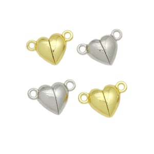 May include: Four heart-shaped magnetic clasps arranged in a square formation. Two clasps are gold-toned and two are silver-toned. Each heart features a smooth, rounded surface with a small circular loop extending from each side for attachment.