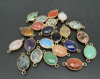 Può includere: Una collezione di connettori per gioielli di forma ovale con pietre preziose sfaccettate in vari colori, tra cui verde, arancione, blu, nero e rosa. Ogni pietra è incastonata in una cornice di metallo dorato con due piccoli anelli alle estremità.