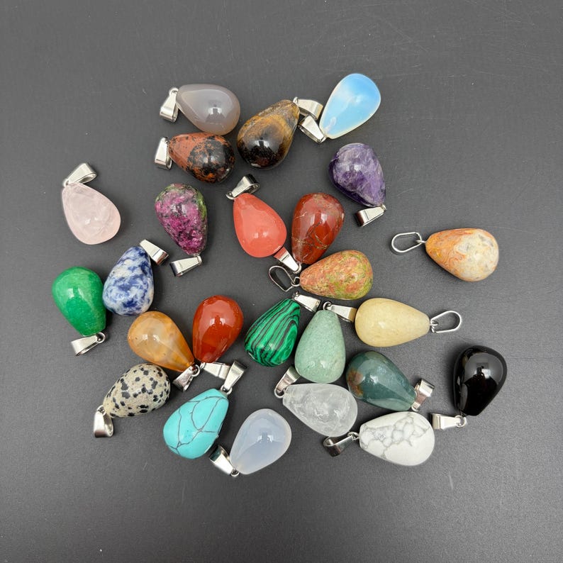 May include: A collection of teardrop-shaped gemstone pendants in various colors and patterns, including rose quartz, amethyst, turquoise, malachite, tiger's eye, and black obsidian, each featuring a silver-toned metal bail for attachment.