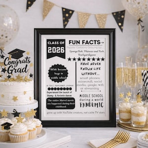 Puede incluir: Una escena de fiesta de graduación con un pastel, cupcakes y un letrero enmarcado. El letrero dice "Clase de 2026" y "Datos divertidos", que enumeran referencias de la cultura pop. Las decoraciones incluyen globos y pancartas doradas y negras, con un adorno para pastel de "Felicitaciones Graduado".
