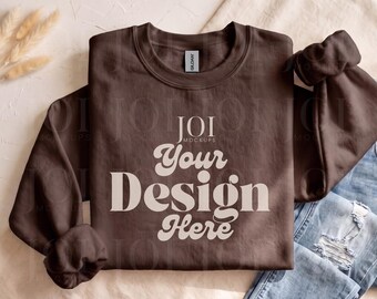 Mockup de moletom Gildan 18000 cor chocolate escuro, modelo Gildan 18000 com gola redonda dobrado e disposto plano, mockup moderno estilo boho.