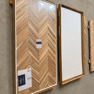May include: Two rectangular solid wood countertops packaged in cardboard frames. The left countertop features a light brown herringbone pattern with a visible product label reading "Solid Wood Countertop" and "Howiz". The right panel is white.
