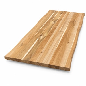 May include: A rectangular wooden tabletop featuring a natural live edge on one side. The surface is composed of multiple joined light brown wood planks with visible grain patterns, knots, and variations in color, showcasing a smooth finish.