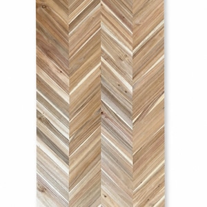 May include: A rectangular wooden panel featuring a natural light brown finish with a prominent herringbone pattern. The surface displays visible wood grain, knots, and variations in color ranging from tan to dark brown, arranged in a vertical chevron design.