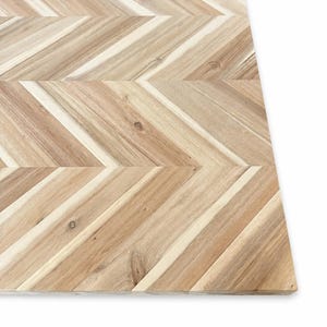 May include: A rectangular wooden board featuring a light brown natural wood grain with a distinct chevron pattern. The surface is composed of multiple angled wooden slats joined together, showcasing variations in color and texture throughout.