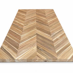 May include: A rectangular wooden cutting board featuring a light and medium brown chevron pattern. The surface is composed of multiple joined wood segments displaying natural grain variations and knots, arranged in a symmetrical herringbone design.