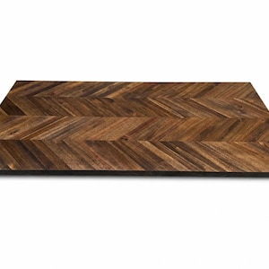 May include: A rectangular wooden tabletop featuring a dark brown finish and a prominent herringbone pattern. The surface displays natural wood grain variations with alternating light and dark brown tones arranged in a repeating chevron design.