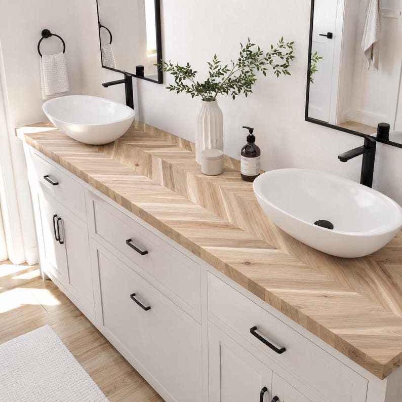 May include: A double bathroom vanity featuring a light wood countertop with a herringbone pattern, two white oval vessel sinks, and matte black hardware. The vanity includes white cabinets with drawers and doors, paired with two black-framed mirrors.