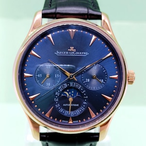 May include: A Jaeger-LeCoultre automatic wristwatch with a rose gold case, a deep blue dial, and a black leather strap. The dial features rose gold hour markers, two sub-dials, a moon phase display, and a date indicator with the text SWISS MADE.