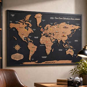 Puede incluir: Un mapa del mundo rectangular para pared con continentes de corcho cortados con láser sobre un fondo negro. El mapa incluye chinchetas de colores, una rosa de los vientos y el texto "Our Love Adventure Since 20180625" en la esquina superior.