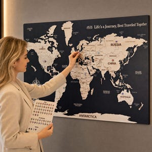 以下が含まれることがあります： 濃紺の背景に明るい木目調の大陸が描かれた、大型の長方形の壁掛け世界地図。右上隅には「Life's a Journey, Best Traveled Together」という文字が印刷されています。さまざまな国に小さな旗のピンが刺されています。