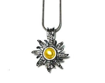 May include: A silver necklace with a sun-shaped pendant featuring a yellow pearl in the centre. The pendant has a detailed design with intricate rays.