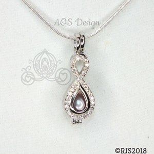 May include: Silver infinity symbol pendant necklace with a pearl inside. The pendant is adorned with clear cubic zirconia stones. The necklace is on a silver chain.