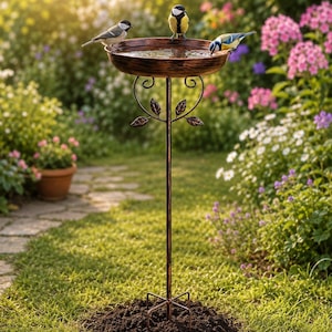 May include: A copper-coloured metal bird bath featuring a circular basin atop a slender stand with decorative scrollwork and leaf accents. Three small birds are perched on the rim of the basin, which is filled with water, supported by a four-pronged base.