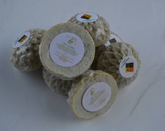 May include: A stack of six round, green, and white soap bars with a floral design. Each bar has a white label with the text "Lime Calamine" and a small image of a flower.