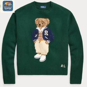 May include: A dark green long-sleeve crewneck sweater featuring a central intarsia-knit graphic of a teddy bear wearing a navy blue varsity jacket, a patterned sweater, beige trousers, and white sneakers. The letters RL are embroidered in white.