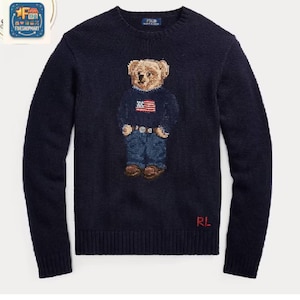 Peut inclure: Un pull bleu marine à manches longues et col rond orné d'un ours en peluche portant un pull sombre avec un drapeau américain, un jean bleu et des chaussures marron. Les lettres RL sont brodées en rouge sur le côté inférieur droit.
