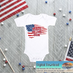 May include: White baby onesie with a distressed American flag design and the text "Made in the USA".