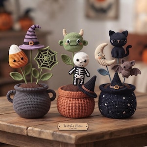 May include: Three crocheted Halloween-themed potted arrangements featuring a candy corn, a spiderweb, a green monster, a skeleton, a crescent moon, a black cat, and a bat. A small wooden sign in front reads Witch's Brew Crochet.