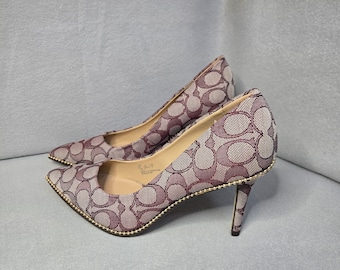 Zapatos de tacón Coach con estampado distintivo y detalles dorados.