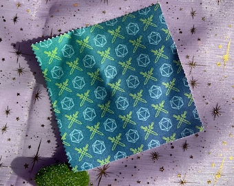 May include: A green and blue fabric with a repeating pattern of dice and swords. The fabric is on a purple background with gold stars.