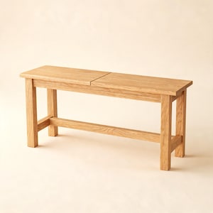 May include: A rectangular wooden bench crafted from light-toned oak with a visible natural wood grain. The bench features a flat seat composed of two joined panels, supported by four sturdy vertical legs connected by a horizontal stretcher bar.