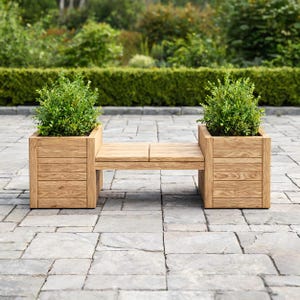 Può includere: Una panca in legno marrone chiaro con due fioriere quadrate alle estremità, ciascuna contenente un arbusto verde brillante. La panca presenta una seduta a doghe ed è realizzata in legno naturale con una venatura visibile su tutta la struttura.
