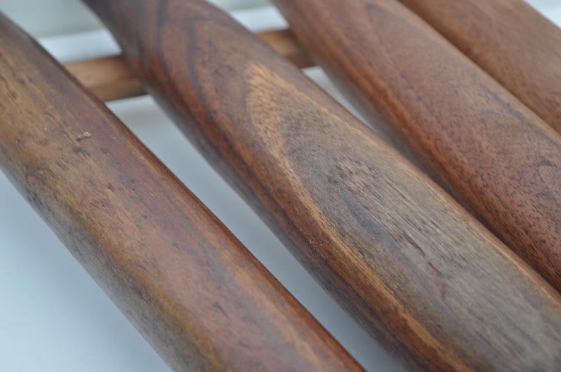 May include: Close-up of several wooden rolling pins with a rich, dark brown finish. The rolling pins are arranged parallel to each other, showcasing the natural wood grain and texture. The image highlights the craftsmanship of the kitchen tools.