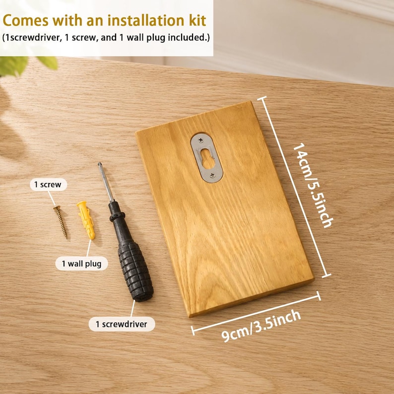 May include: A rectangular light brown wooden board with a metal keyhole hanger, accompanied by an installation kit containing one screwdriver, one screw, and one wall plug. The board measures 5.5 inches by 3.5 inches as indicated by text.