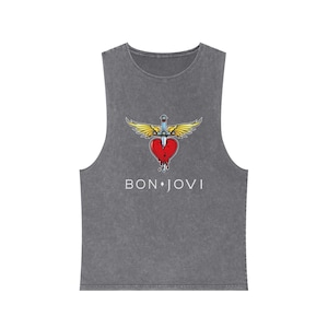 May include: A charcoal gray sleeveless tank top with a vintage wash finish. The center graphic features a red heart pierced by a silver dagger with yellow wings. Below the graphic, the text BON JOVI is printed in a clean, white sans-serif font.